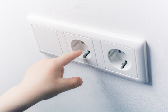 Child Tries To Touch A Wall Socket Without Safety Plugs - Prevent Child Hazard Concept