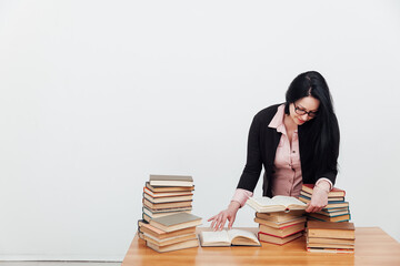 beautiful female teacher in business suit at a table with stacks of educational books