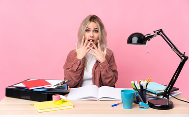 Young student woman working in a table with surprise facial expression