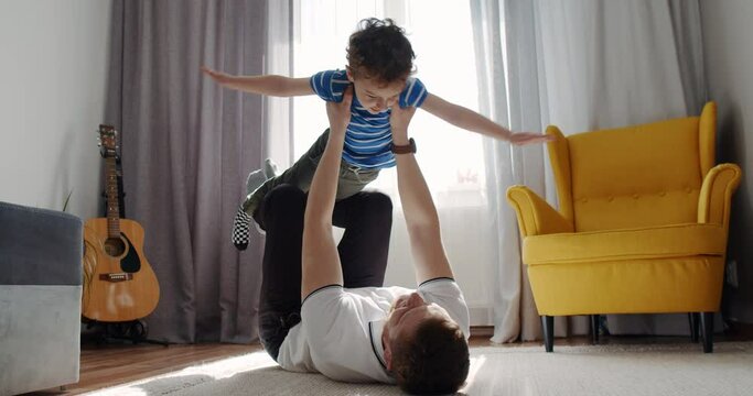 Sport time at home in the living room dad with his small cute son. 