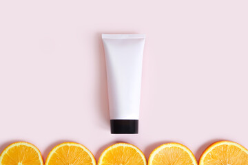 Pink squeeze bottle cream tube with black cap and orange slices on pink background. Top view, mockup, flatlay. Cosmetic skincare product blank plastic package. Vitamin c concept.