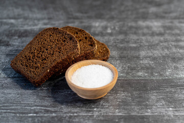 Organic rye bread with salt, ready to eat on gray wooden background