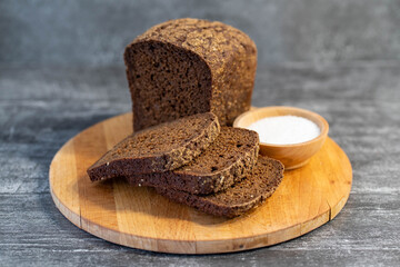 Organic rye bread with salt, ready to eat on gray wooden background