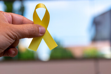 Yellow September: Suicide Prevention Awareness Month. hand holding ribbon with yellow bow,...