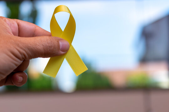 Yellow September: Suicide Prevention Awareness Month. hand holding ribbon with yellow bow, representing accident prevention campaign. Yellow May.