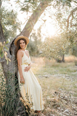 Tender portrait of beautiful brunette woman in beautiful sunlight. Woman in yellow summer linen dress in olive tree garden. Natural beauty.Travel to Italy, summer vacation