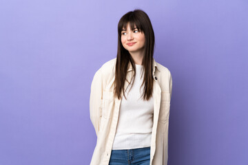 Obraz premium Young Ukrainian woman isolated on purple background making doubts gesture looking side