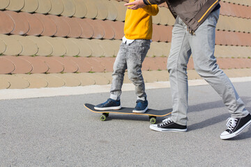 Fototapeta na wymiar Father is teaching his son to ride a skateboard, outdoors