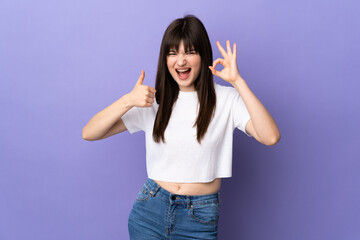 Young Ukrainian woman isolated on purple background showing ok sign and thumb up gesture