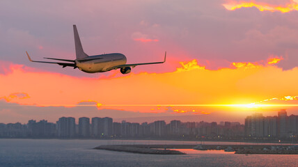 Fototapeta na wymiar Passenger airplane flying over the city at sunset