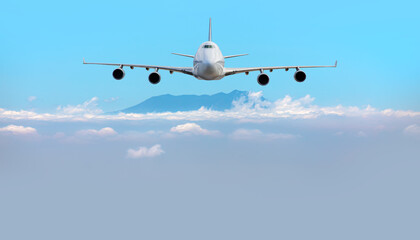 A passenger airplane flying over the clouds and a mountain peak in the background