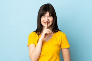 Teenager Ukrainian girl isolated on blue background showing a sign of silence gesture putting finger in mouth