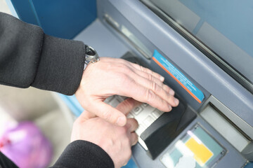 Naklejka premium Man enters code on ATM keyboard and closes it with his hand