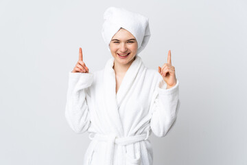 Teenager girl in a bathrobe isolated on white background pointing up a great idea