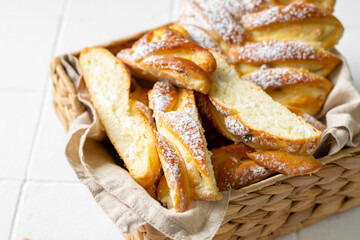 Sweet bun with cottage cheese and raisins in a basket on the white kitchen table close-up. The concept of home-made high-calorie pastries