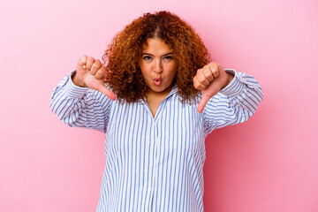 Young latin curvy woman isolated on pink background showing thumb down and expressing dislike.