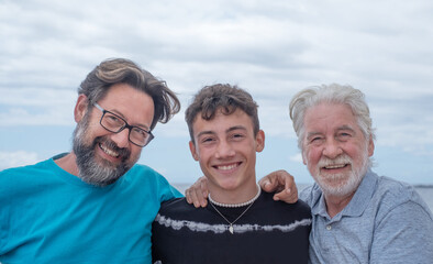 Three generations of family, hug smiling happy, father, teenage son and grandfather. Handsome people relaxing together