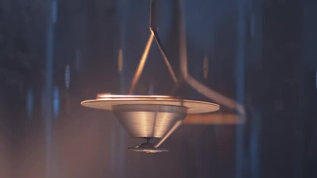 Super slow motion: hanging metal gyroscope spinning top pendulum - interactive exposition at science exhibition museum - close up. Physics, experiment, education, laboratory equipment concept