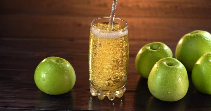 close-up of pouring juice into a glass. there are fresh red apples on the table nearby. 4k video