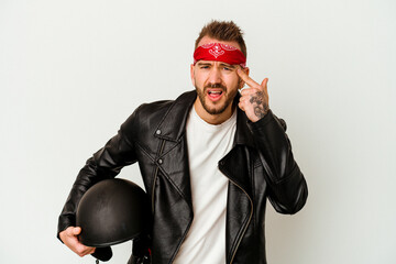 Young biker tattooed caucasian man holding a helmet isolated on white background showing a disappointment gesture with forefinger.