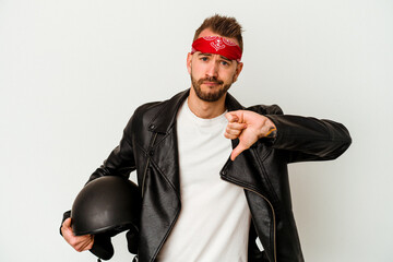 Young biker tattooed caucasian man holding a helmet isolated on white background showing a dislike...