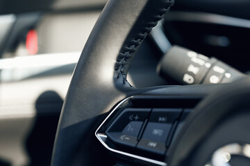 Obraz premium Multimedia leather steering wheel in a modern expensive car. Black leather steering wheel. Modern car interior details. Selective focus. Part of stitched leather black leather car interior. Macro shot