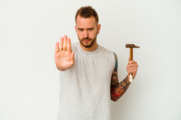 Young tattooed caucasian man isolated on white background standing with outstretched hand showing stop sign, preventing you.