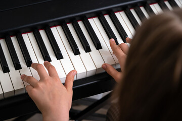 Closeup of teenager playing piano in home music studio. Girl having online class and practicing on modern electric piano