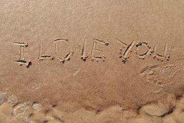 I love you sign whiten on the sand at the beach. Romantic love symbol at tropical seashore at sunset.