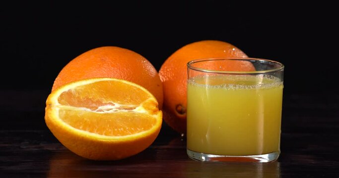 Man's hand takes the glass of orange juce from the dark table