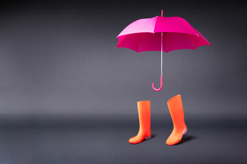 Rubber shoes and umbrella isolated on black background. Rain season and weather forecast. Nobody