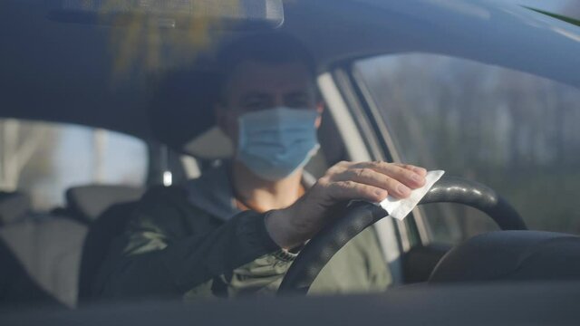 Man clean steering wheel using wet wipes. Man protect himself and clean car inside using antiseptic