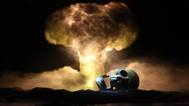 Nuclear war concept. Explosion of nuclear bomb. Creative artwork decoration in dark. Silhouette of grim reaper looking on giant mushroom cloud of atomic explosion. Selective focus
