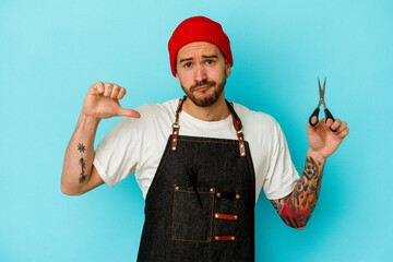 Young tattooed barber man isolated on blue background feels proud and self confident, example to follow.