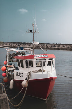 NORTHERN IRELAND, UK - 8TH APRIL 2019: A bright red fishing boat called Bold Venture is moored at a port in Ireland