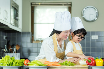 Cooking Family. Chef kid boy and mother making and leaning fresh vegetables salad for healthy eat and education.  Asian son helping make food, so happy and enjoy
