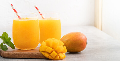 Fresh mango juice smoothie in a glass cup on gray table background.