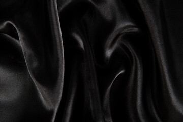 Fototapeta premium Abstract black silk fabric texture background. Cloth soft wave. Creases of satin