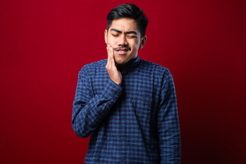 Obraz premium Young handsome man wearing casual shirt standing over isolated red background touching mouth with hand with painful expression