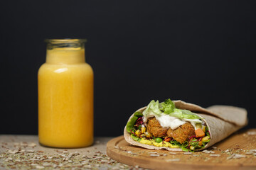 juice next to healthy vegetarian tortilla on wooden plate