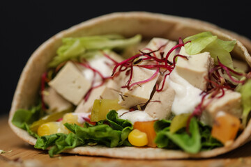 Close up of juicy healthy vegetarian tortilla on wooden plate
