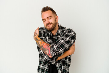 Young tattooed caucasian man isolated on white background hugs, smiling carefree and happy.