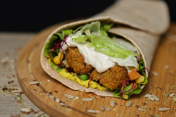 Close up of juicy healthy vegetarian tortilla on wooden plate