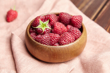 Fresh raspberries in wooden bowl on brown table. Red ripe raspberries, sweet berries