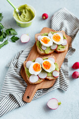 Healthy avocado and egg toasts for breakfast on board, top view, natural lighting