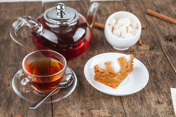 Set with teapot, cup and a slice of honey cake on the wooden table