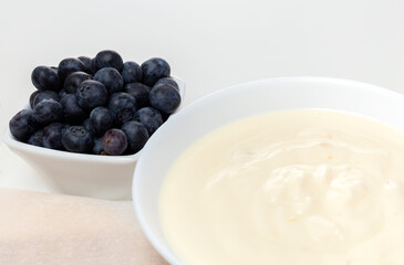 Blueberries and Yogurt in a white vase on a white table. Ingredients for dessert. Copy space. High quality photo