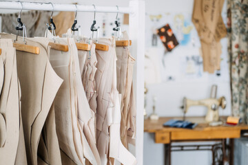 Many paper sewing patterns for different clothes hanging on the rack in sewing factory background. Clothing pattern, manufacture on sewing factory. Tailoring, small business - Powered by Adobe