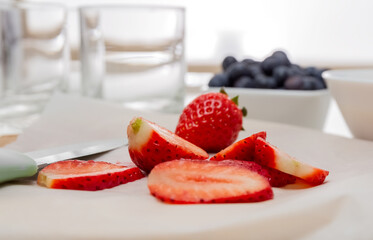 Chef's knife and slices of strawberries on a cutting board. Baking paper. Healthy food concept. High quality photo