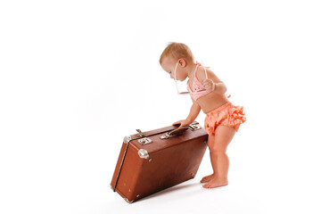Amusing funny Little Toddler in a bathing suit and sunglasses with a retro suitcase, isolate on a white background. Travel concept with children, travel fees and dreams of the sea